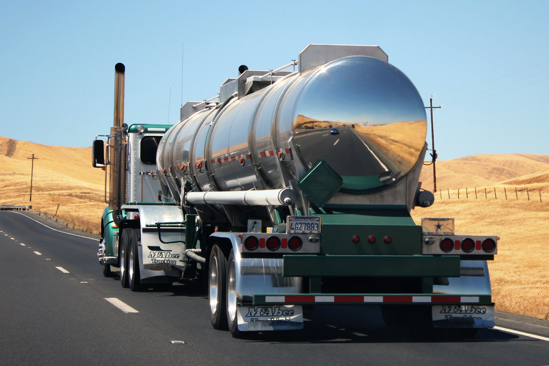 A tanker truck on a two-lane highway through dry hills